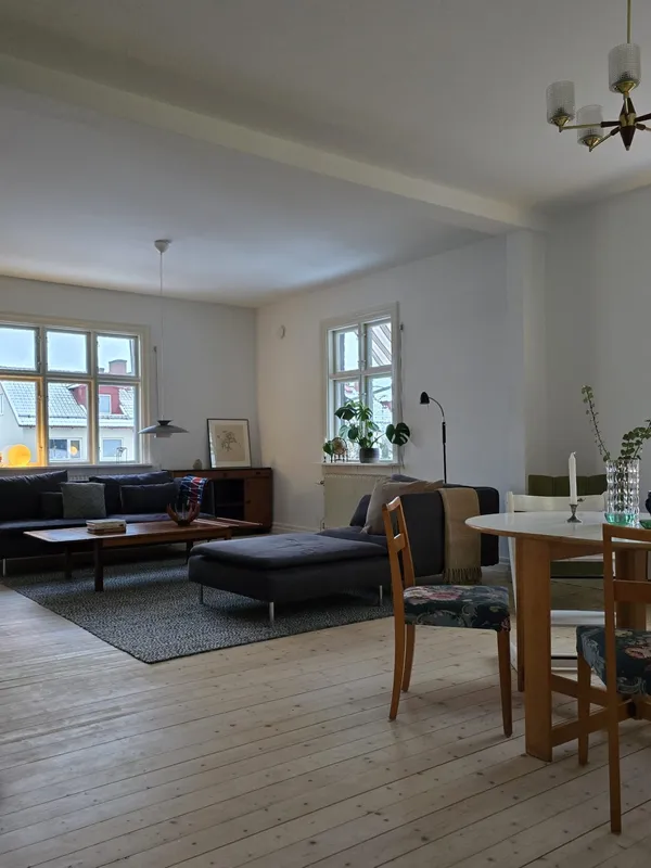 Vardagsrum och matsal med ljust trägolv och mörkblå soffa, renoverat