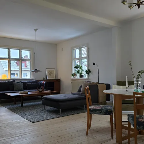 Vardagsrum och matsal med ljust trägolv och mörkblå soffa, renoverat