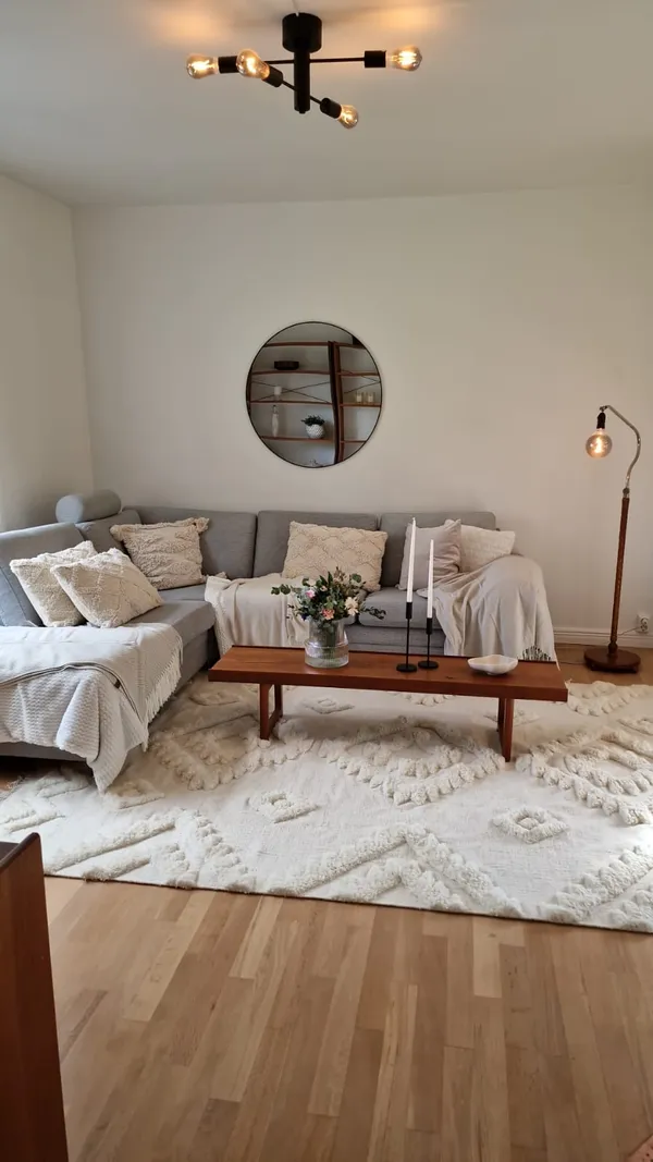 Renoverat vardagsrum med grå soffa och vit matta